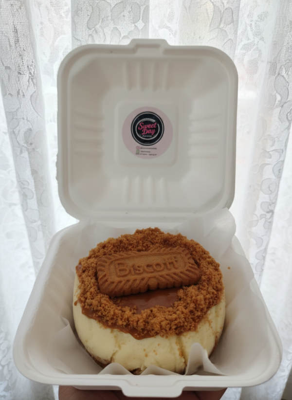 Biscoff cheesecake in takeaway box topped with lotus biscoff biscuit and crumbs